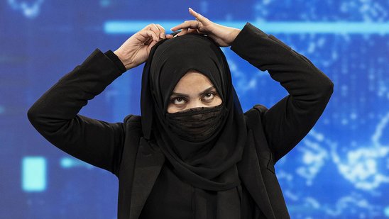 Une présentatrice de la chaîne afghane TOLOnews, Thamina Usmani, couvre son visage avec un voile durant une émission en direct, Kaboul, le 22 mai 2022. (Crédit photo : AFP / WAKIL KOSHAR)