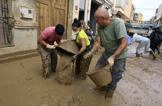 Des habitants nettoient leurs maisons  en évacuant la boue à Massanassa, dans la région de Valence (Espagne), le 8 novembre 2024 (Crédit photo : AFP / JOSE JORDAN)