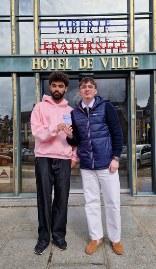 Deux étudiants de BTS devant l'Hôtel de Ville d'Avranches, carte électorale en main, illustrant leur engagement citoyen. (Crédit photo : Lycée NDLP - Avranches)